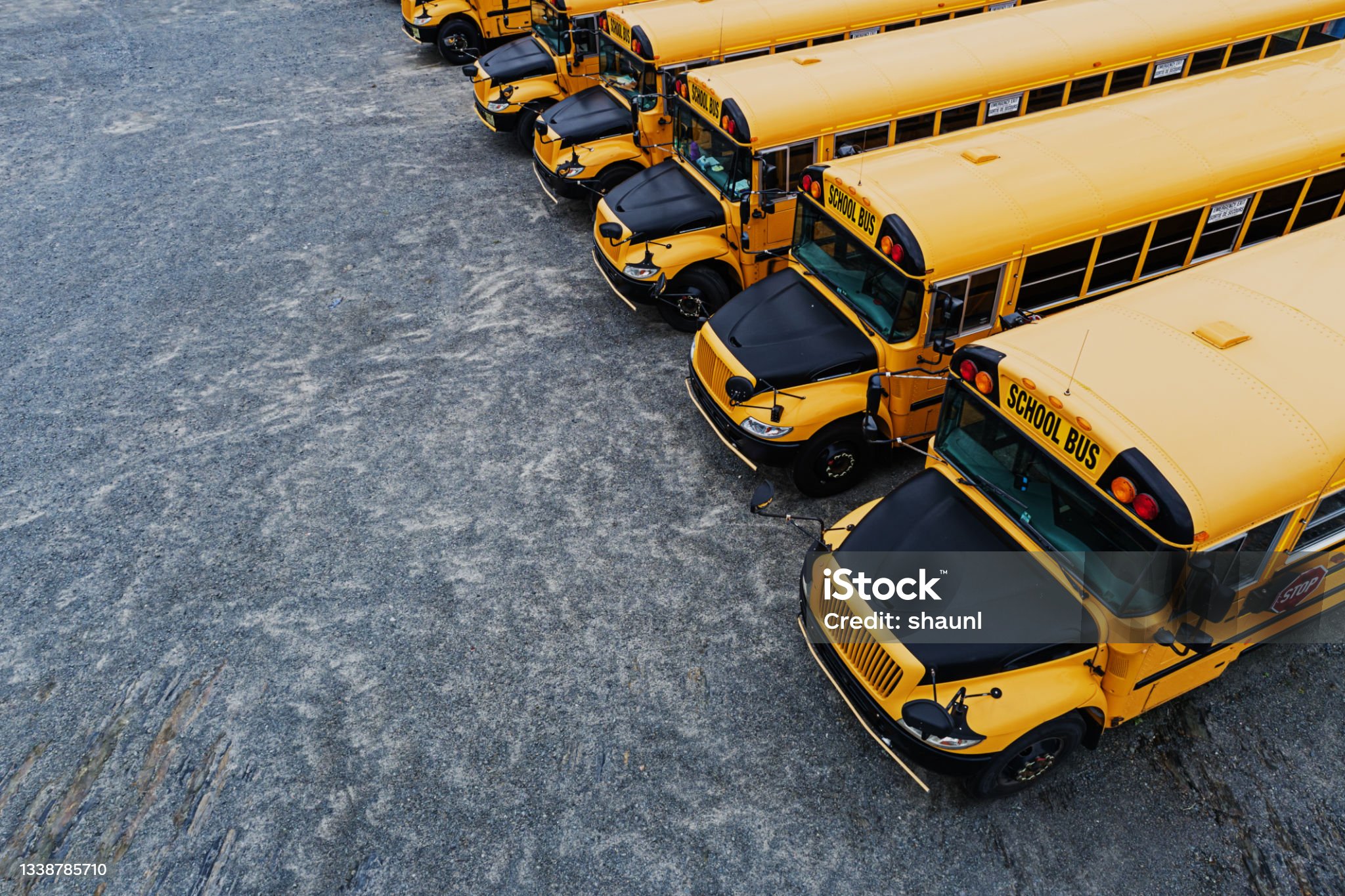 Aerial view of school buses stored in a gravel lot on a weekend.