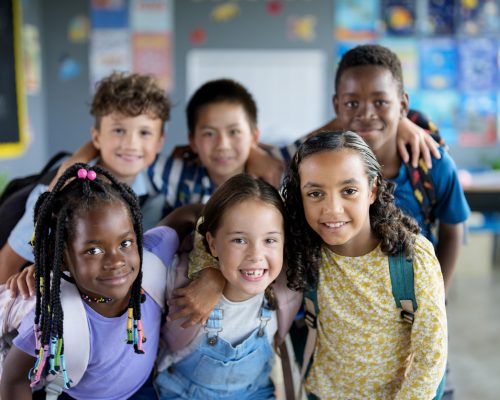 A vibrant group of diverse school children smiling and enjoying their time learning in a classroom environment, highlighting friendship, education, and inclusion.